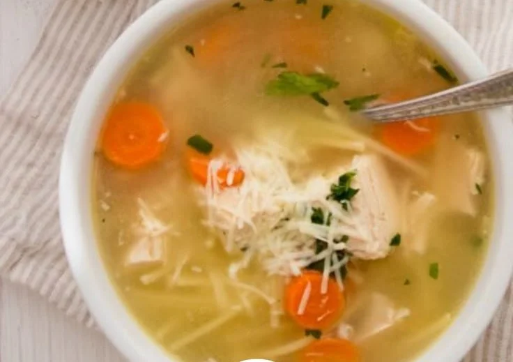 Bowl of Giada's lemon chicken soup with spaghetti garnished with parsley