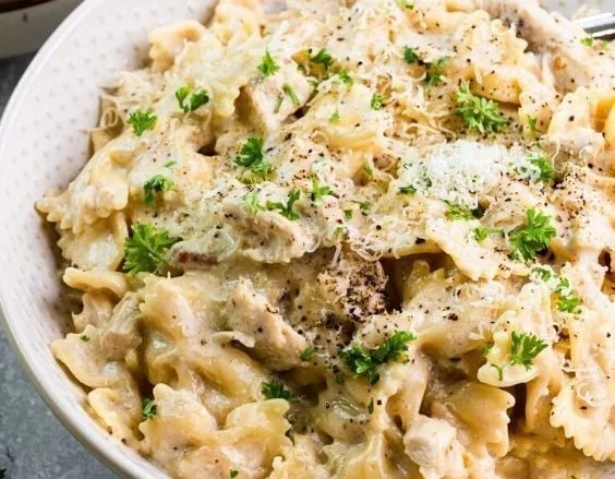 Creamy Instant Pot Chicken Alfredo served with fettuccine and parsley garnish.